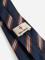 A close-up of the BGcarl Tie in Dark Navy, a luxury silk striped tie by Blue de Gênes, showcases brown and white diagonal lines and features a label with the brand’s name alongside a small red and white shield logo.