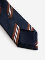 A close-up of the BGcarl Tie - Dark Navy by Blue de Gênes, featuring diagonal brown and white stripes on navy blue silk, displayed on a white background.