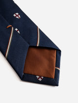 A close-up of the BGshield Tie - Dark Navy by Blue de Gênes, showcasing its navy hue with shield motifs and diagonal stripes, complemented by a contrasting brown inner lining at the tip for a refined finish.