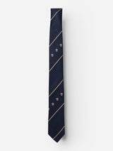 The BGshield Tie - Dark Navy by Blue de Gênes is expertly crafted from luxurious silk in a deep navy hue, adorned with diagonal tan stripes and subtle shield motifs. Presented against a plain white background, this elegant accessory is distinguished by the refined Blue de Gênes logo, adding a touch of sophistication.