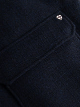 Close-up of the BGdugal Bomber Jacket in Dark Navy by Blue de Gênes, featuring a dark wool blend fabric and a flap pocket adorned with a small metallic shield-shaped pin with a cross at its edge.