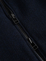 Close-up of a black zipper on dark navy fabric from the BGdugal Bomber Jacket by Blue de Gênes. The partially open zipper reveals its teeth and slider, while the wool blend fabric displays a slightly fuzzy texture.