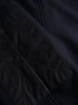 Close-up of a dark waxed cotton patch with diagonal X-pattern stitching on the BGBoyd Wool Jacket in Dark Navy by Blue de Gênes.