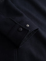 Close-up of the BGBoyd Wool Jacket - Dark Navy by Blue de Gênes, showing the sleeve’s thick, textured wool fabric and a cuff finished with a matte black button alongside a shiny silver snap—details inspired by classic durable workwear.