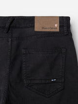 Close-up of the back pocket area of navy BGvinci Iro Pant from Blue de Gênes, crafted from comfort stretch twill, featuring a brown leather patch reading Blue de Gênes stitched above the pocket and a small blue tag on the pocket edge.