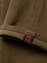 Close-up of a beech green fabric cuff with visible texture, featuring a folded edge and two parallel red stitches on the seam—crafted from Blue de Gênes’ BGvinci Iro Pant comfort stretch twill for enhanced ease and durability.