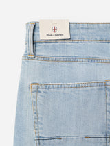 Close-up of the back pocket and waistband of BGvinci Trueblue Jeans in mid blue denim by Blue de Gênes, featuring comfort stretch and a white tag with the brand’s red and black logo tucked into the waistband.