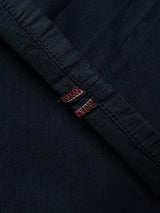 Close-up of the BGmenzo Vecchio Chino - Dark Navy by Blue de Gênes, featuring dark denim-inspired fabric with prominent seams and distinctive red and white stitching accents, evoking a vintage aesthetic combined with contemporary style.
