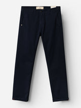 The BGmenzo Vecchio Chino in Dark Navy by Blue de Gênes is a pair of straight-leg chinos featuring side pockets, belt loops, and a button closure. Crafted with comfort stretch for all-day wear and shown flat against a white background, these chinos are perfect for achieving that timeless vintage look.