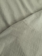 Close-up of soft, slightly wrinkled slub cotton in light gray with a diagonal seam, similar to the texture found on the Blue de Gênes BGoscar T-Shirt in Shadow Green.