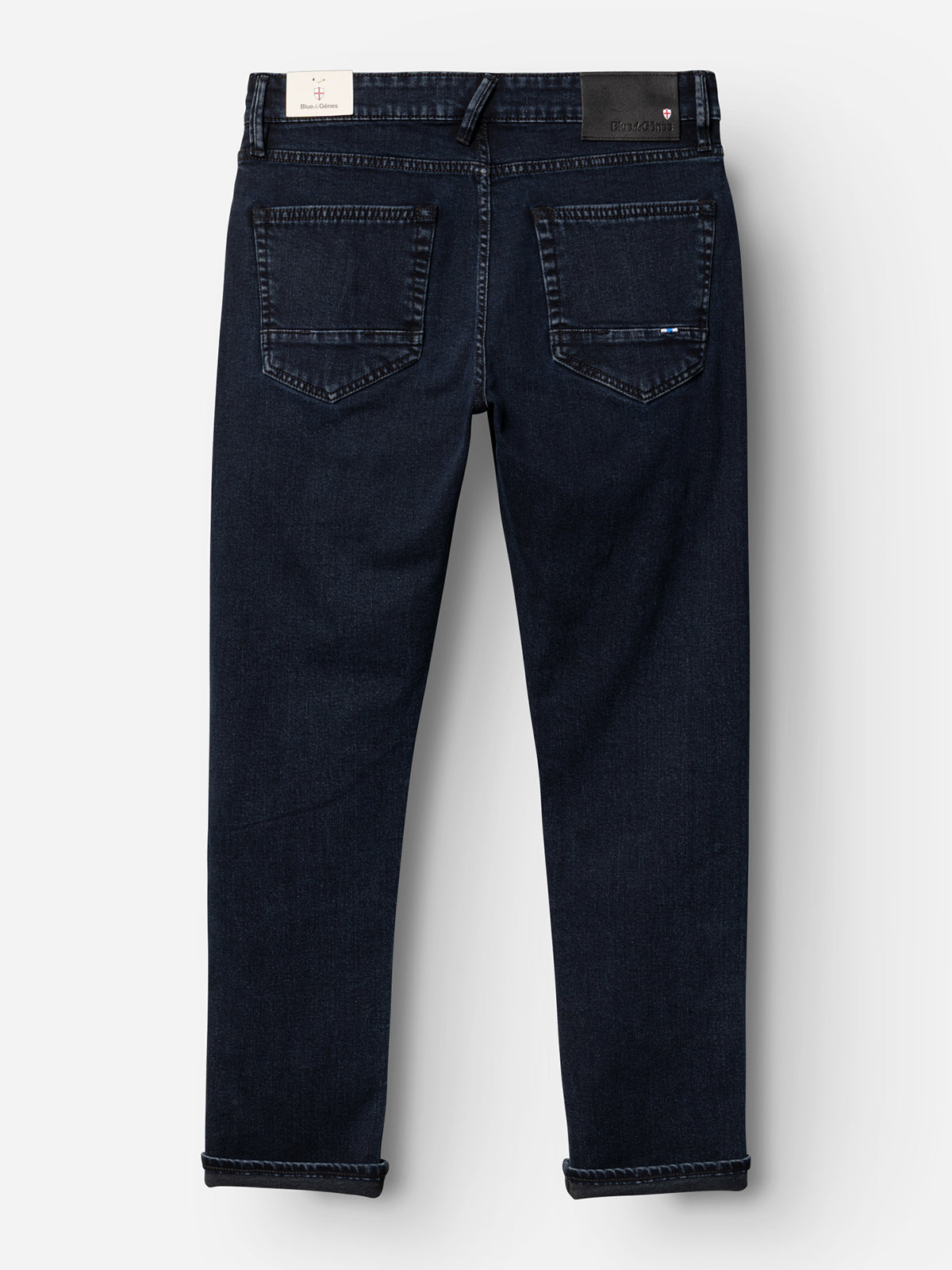The BGvinci Black OD Jeans by Blue de Gênes, in blue black stretch denim, are shown from the back with two rear pockets, rolled cuffs, and black and white brand labels on the waistband.