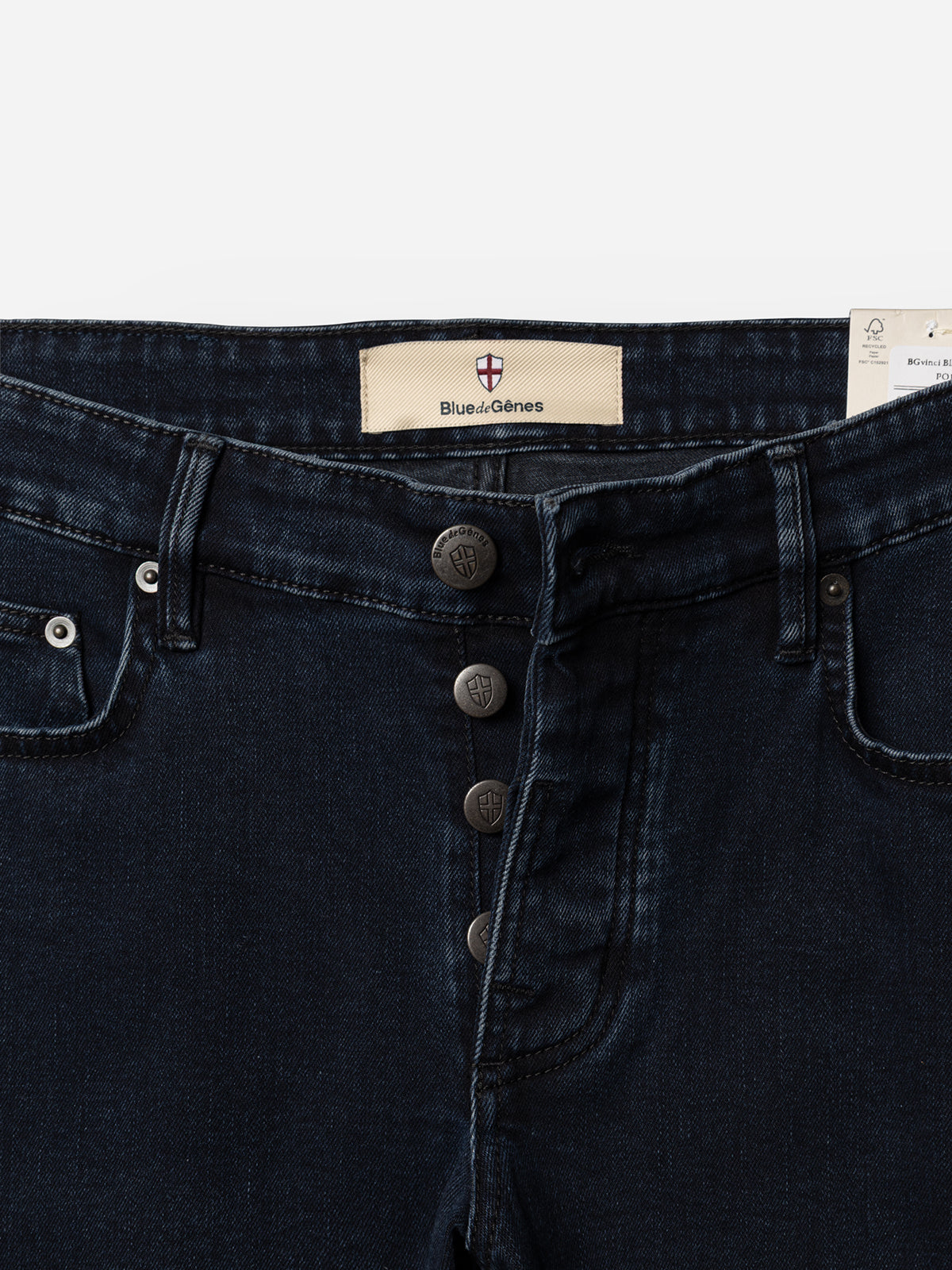 Close-up of the waistband and fly on BGvinci Black OD Jeans by Blue de Gênes in blue-black denim, featuring a comfort stretch fit, five pockets, four visible metal buttons, front pockets, and an inner waistband label with the brand name.