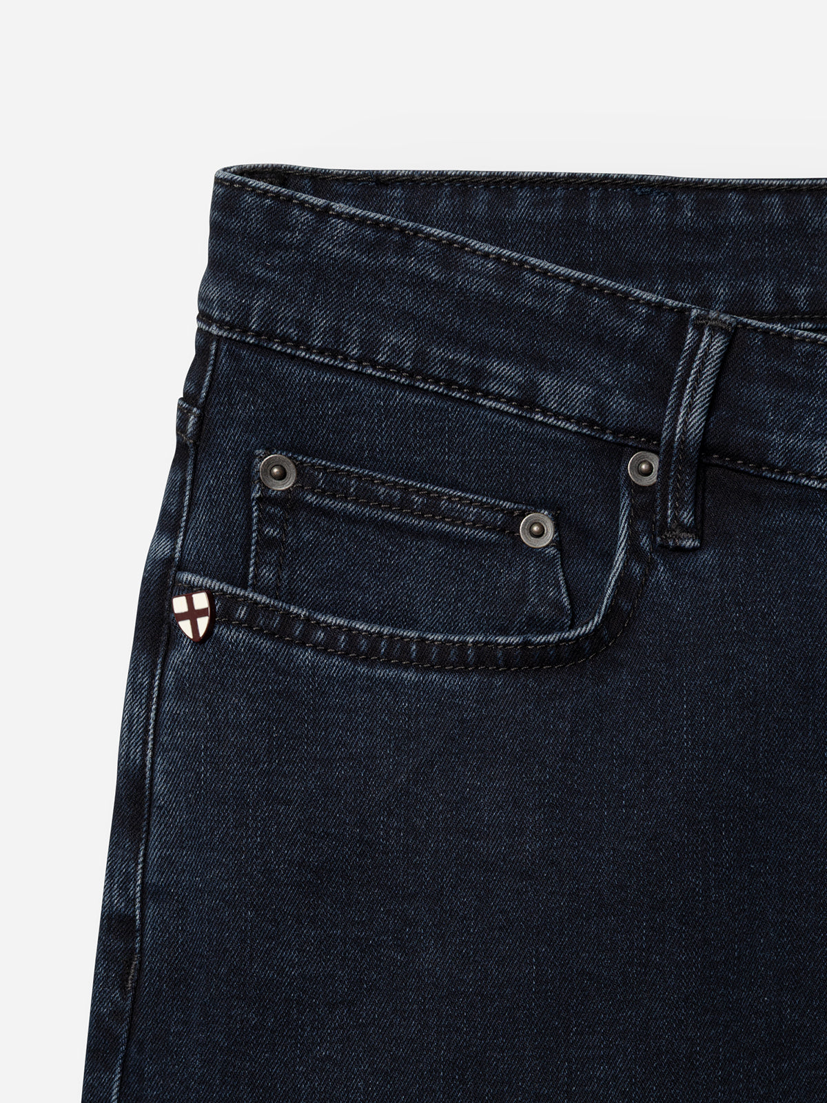 Close-up of the upper section of Blue de Gênes BGvinci Black OD Jeans in blue black denim, featuring comfort stretch and a front pocket with a small white and red shield emblem stitched on the coin pocket.