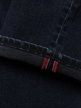 Close-up of the cuff of BGvinci Black OD Jeans by Blue de Gênes in blue black denim, showcasing a rolled hem with visible red and white selvedge stitching detail.