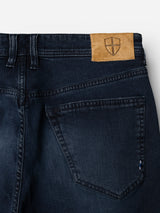 Introducing the BGgiacomo BB Jeans by Blue de Gênes—crafted in rigid blue-black denim, these jeans feature a relaxed loose fit, back pocket detailing, sturdy belt loops, and a tan leather patch with a shield emblem stitched onto the waistband.