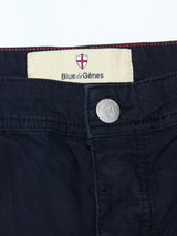 Close-up of the waistband on the BGpaulo Teo Pant - Dark Navy by Blue de Gênes, featuring a metal button engraved with the brand name and an interior cream label with a red cross shield, highlighting these durable chinos inspired by vintage military pants.