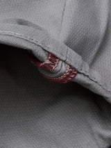 Close-up of the Flint gray fabric from the BGpaulo Teo Pant by Blue de Gênes, highlighting its textured weave, detailed seam, and a loop of red and white thread stitching—showcasing craftsmanship reminiscent of vintage military pants or durable heritage chinos.