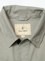 Close-up of the BGpontus Teo Overshirt in Shadow Green, a relaxed fit shirt from Blue de Gênes, featuring a red and white shield logo label sewn inside the neckline and buttoned at the top.