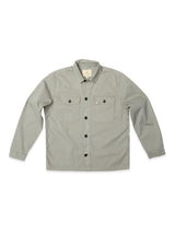 The Blue de Gênes BGpontus Teo Overshirt in Shadow Green is a relaxed-fit overshirt, featuring long sleeves, a collar, and two chest pockets with flaps and buttons. It is displayed laid flat on a white background.