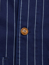 Close-up of the Blue de Gênes BGkendrick Toll Jacket in Navy Stripe, featuring thin white vertical stripes on blue cotton and a brown four-hole button near the center, highlighting its relaxed fit and classic worker jacket style.