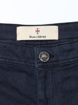 Close-up of the navy Menzo Olanda Chino waistband from Blue de Gênes, featuring a metal button, dark stitching, and a Blue de Gênes label with shield logo, styled with a tapered leg fit.