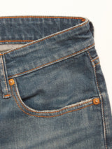 Close-up of the front pocket area of Blue de Gênes Vinci Topaz Vintage Jeans - Used in blue, featuring orange stitching and metal rivets, made in Italy, highlighting the texture and detail of the comfort stretch denim fabric.