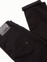 A pair of folded Vinci Venom Blk Jeans - Dark Denim by Blue de Gênes, featuring a regular fit in black with visible back pocket stitching, a small tricolor tag, and a black leather brand patch on the waistband, made in Italy.