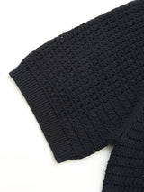 Close-up of the BGbilly S/S Cardigan in Dark Navy by Blue de Gênes, showcasing its black textured knit fabric with a waffle or grid pattern and ribbed cuff detail on a white background—crafted from 100% cotton for soft comfort and vintage-inspired appeal, reminiscent of a classic knit cardigan.