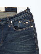 A close-up of Blue de Gênes Repi Dark Vintage Jeans in mid blue denim, highlighting the front and coin pockets, belt loop, waistband with orange stitching, and a tag visible inside.