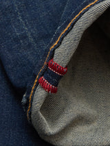Close-up of the cuff of Blue de Gênes Repi Dark Vintage Jeans - Mid Blue Denim, showing slim-fit raw selvedge denim with a dark vintage wash, white stripe with red edge stitching, and contrasting yellow seam stitching.