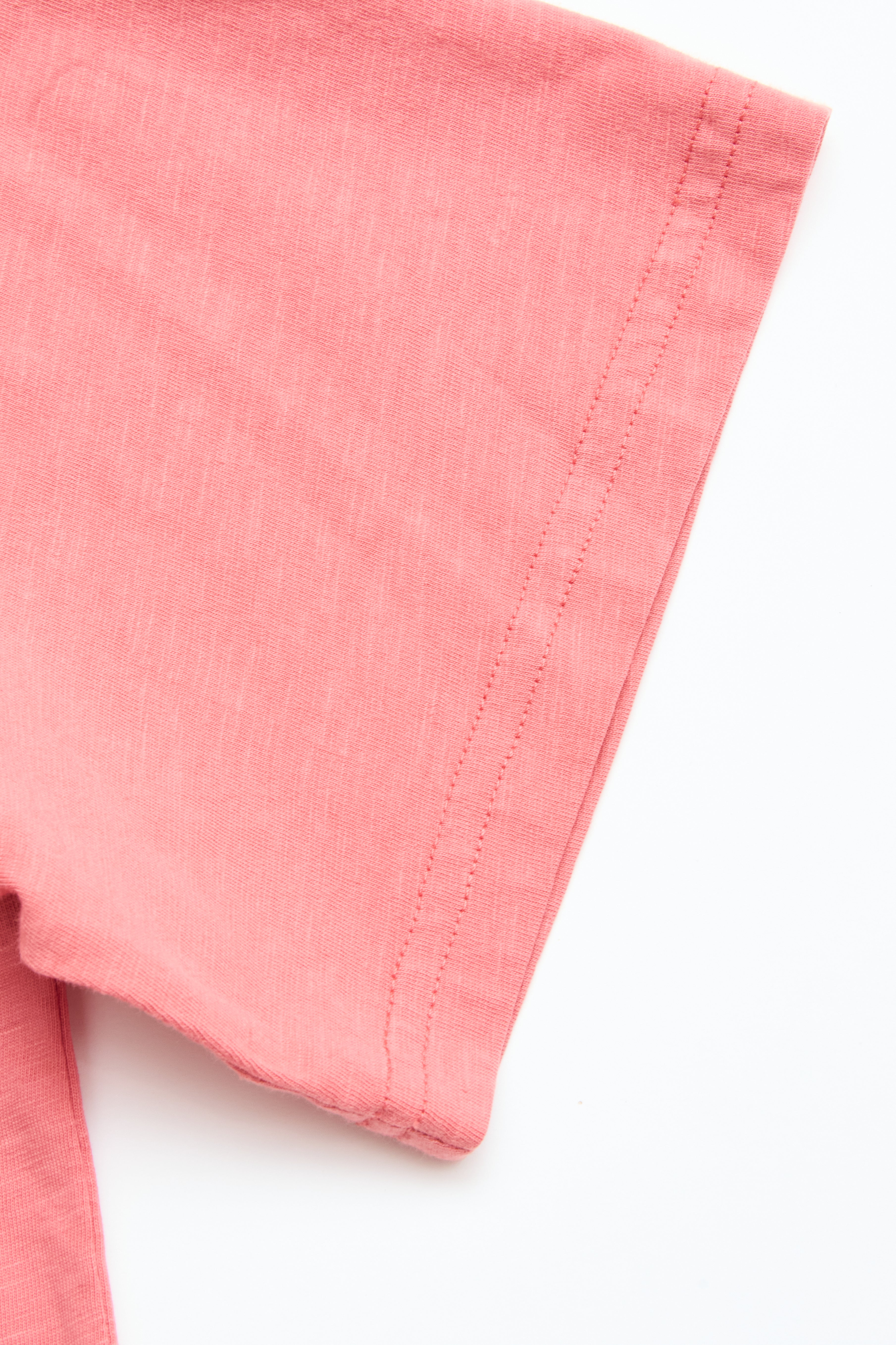 Close-up of the BGoscar T-Shirt - Coral by Blue de Gênes, featuring short sleeves and careful hem stitching in soft pink 100% cotton, set against a white background.