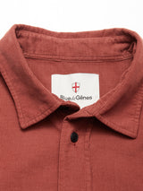 A close-up of the Zamboni Velu Shirt in Henna by Blue de Gênes, featuring rust-colored corduroy, a collar, single black button, and an inside label with a red shield.
