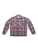 The Yodo Check Overshirt by Blue de Gênes is a relaxed fit, long-sleeve button-up flannel in a blue, red, and white plaid with two chest pockets featuring diagonal plaid designs and buttoned flaps.