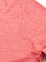 Close-up of the BGmonty Knit - Coral by Blue de Gênes, a pink short-sleeve shirt made from a cotton-linen blend, highlighting the textured fabric and detailed seams on the sleeve and shoulder.