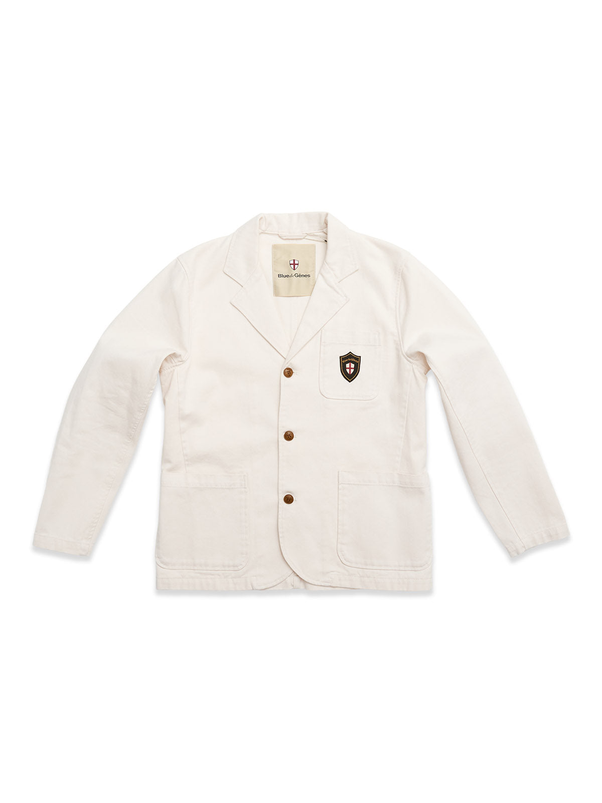 The Blue de Gênes BGbaio Twill Blazer in Chalk is a classic white cotton jacket with brown buttons, two front pockets, and a black and red shield patch on the left chest. Regular fit, shown flat on a white background.