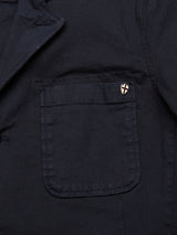 Close-up of the Gabbiano Dobby Blazer - Dark Navy by Blue de Gênes, featuring a pocket with a stylish small pin—white background, red cross, black border—attached at the top edge. Crafted for comfort with cotton stretch.