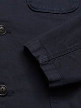 Close-up of Blue de Gênes Gabbiano Dobby Blazer in dark navy, highlighting the cotton fabric, sleeve, front pocket, and two black buttons with detailed stitching inspired by vintage janitor blazers.