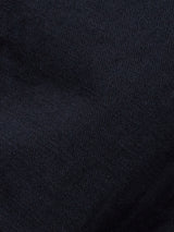 Close-up of the dark navy fabric from the Blue de Gênes Gabbiano Dobby Blazer, showing its textured woven surface and soft lighting that accentuates the intricate weave pattern.