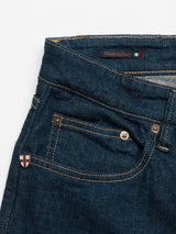 Close-up of the Vinci Topaz Jeans - Rinse Wash by Blue de Gênes featuring blue comfort stretch denim, a front pocket with a small badge, bronze rivets, and a Made in Italy label with an Italian flag inside the waistband.