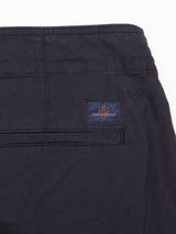Close-up of the back pocket area of the Mustang Cargo Pant - Navy by Blue de Gênes, featuring a small rectangular patch with a red and white logo and the text Thick as Thieves above the pocket.