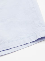 Close-up of the hem on Blue de Gênes Menzino Shorts - Blue Water, highlighting the stitching and texture of the light blue cotton-linen blend fabric against a white background.