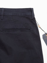 Close-up of the upper back of Blue de Gênes Menzo Dobby Chino - Dark Navy, featuring a single welt pocket, belt loops, subtle embroidered logo, and attached tags hanging from the waistband.