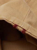 Close-up of tan Menzo Dobby Chino - Khaki by Blue de Gênes, showing fabric texture, visible stitching, and two dark red thread sections along the seam at the hem.