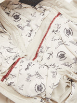 Close-up of the Menzo Dobby Chino - Stone by Blue de Gênes, showing white cotton lining with black script, anchor motifs, stamp-like designs, and detailed red stitching for a vintage look.