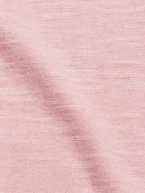 A close-up of Blue de Gênes’ Monte Knit in Porcelain Pink shows its soft, slightly textured weave and a gentle diagonal crease across the fabric.