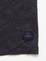 A close-up of the Totti T-Shirt - Dark Navy by Blue de Gênes shows the bottom hem with a small navy patch, orange shield, and branding details.