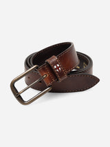 Introducing the BGualan Belt - Brown from Blue de Gênes: a coiled, full-grain brown leather belt featuring tan stitching, an antique brass buckle, and a small red, white, and blue stitched emblem on the belt loop near the buckle. Handcrafted in Italy.