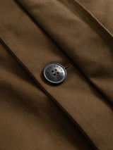 Close-up of the BGjacques AW Coat - Brown by Blue de Gênes, crafted from heavy cotton fabric in a rich brown hue. The coat features a single black button inscribed with GENZO BLUE, neatly sewn on with brown thread, adding a classic workwear charm to this relaxed outerwear piece.
