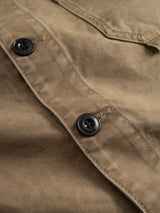 Close-up of the BGcuddy Nebraska Jacket in brown by Blue de Gênes, featuring two black buttons and visible stitching details. The high-density cotton material showcases its texture and seams, emphasizing the jacket’s durable construction.