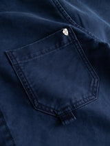 Close-up of the BGcuddy Nebraska Jacket - Blue by Blue de Gênes, highlighting the dark blue cotton workwear pocket with visible stitching and a small round silver button at the top corner, showcasing the high-density dobby weave characteristic of premium utility jackets.